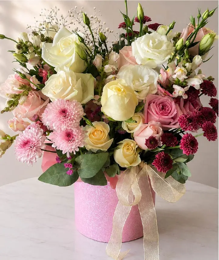 Caja floral premium con rosas blancas, rosas rosadas, lisianthus y flores decorativas en tonos suaves presentada en elegante caja rosada para regalo en Costa Rica.
