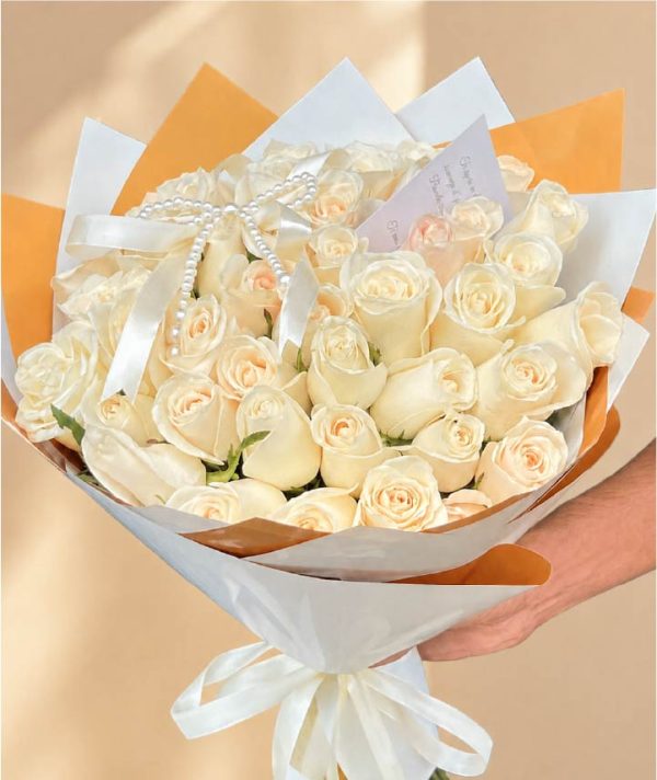 ramo-buchón-premium-de-48-rosas-champagne-elegance Ramo premium de rosas blancas con elegante envoltura y listón satinado.