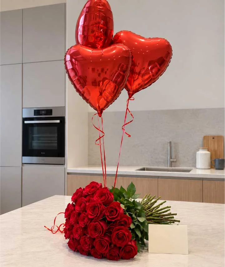 Ramo de 48 rosas rojas premium acompañado de globos metálicos rojos en forma de corazón.
